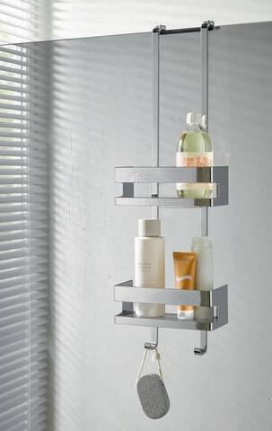 Ein Chrom-Duschablage mit zwei Regalen hält Flaschen mit Shampoo, Duschgel und Körperlotion. Vertikaljalousien verdecken teilweise ein nahegelegenes Fenster.