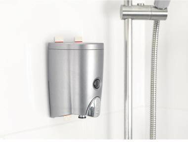 Edelstahlseifenspender an der Wand neben einer Duschstange im Badezimmer.