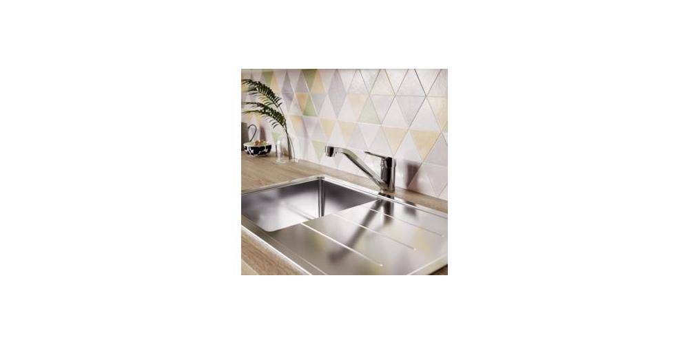 Edelstahlküchenbecken mit Einhebelmischer in eine Holzarbeitsplatte eingebaut, vor einem geometrischen Fliesenspiegel.
