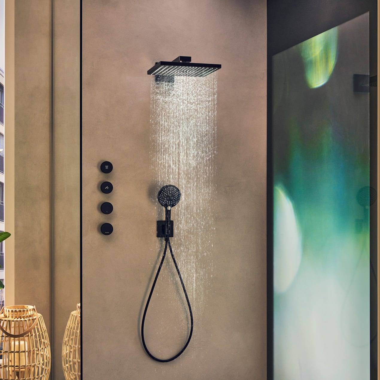 Modernes Badezimmer mit quadratischer Regendusche von oben und tragbarem Handbrausekopf an einer beige Badezimmerwand, mit Bedienungselementen daneben.