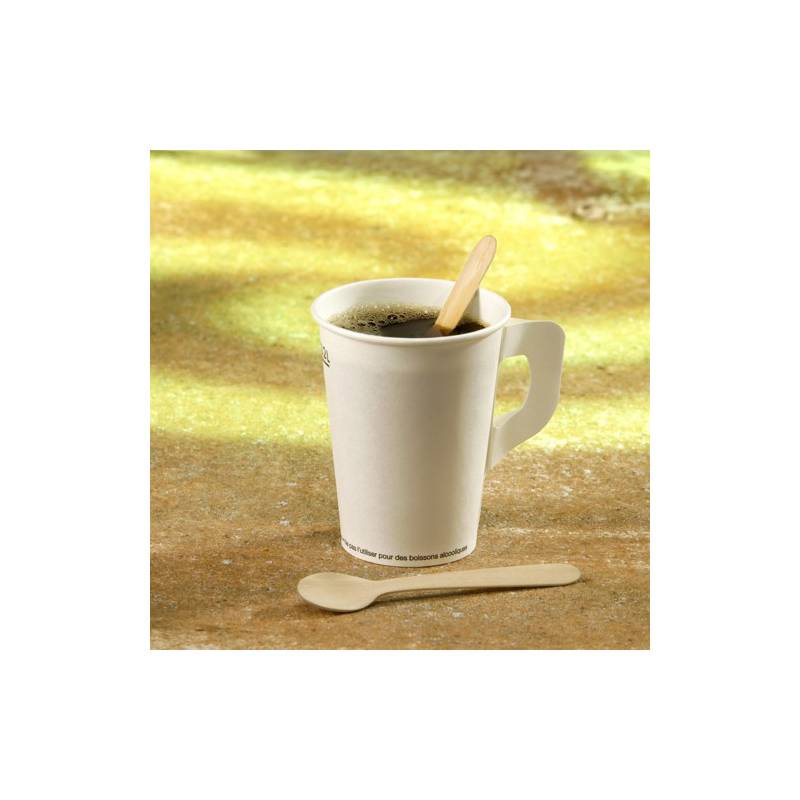 Eine Papierkaffeetasse gefüllt mit Kaffee, ein Holzrührerstab im Inneren und ein kleiner Löffel daneben, auf einem strukturierten Hintergrund.