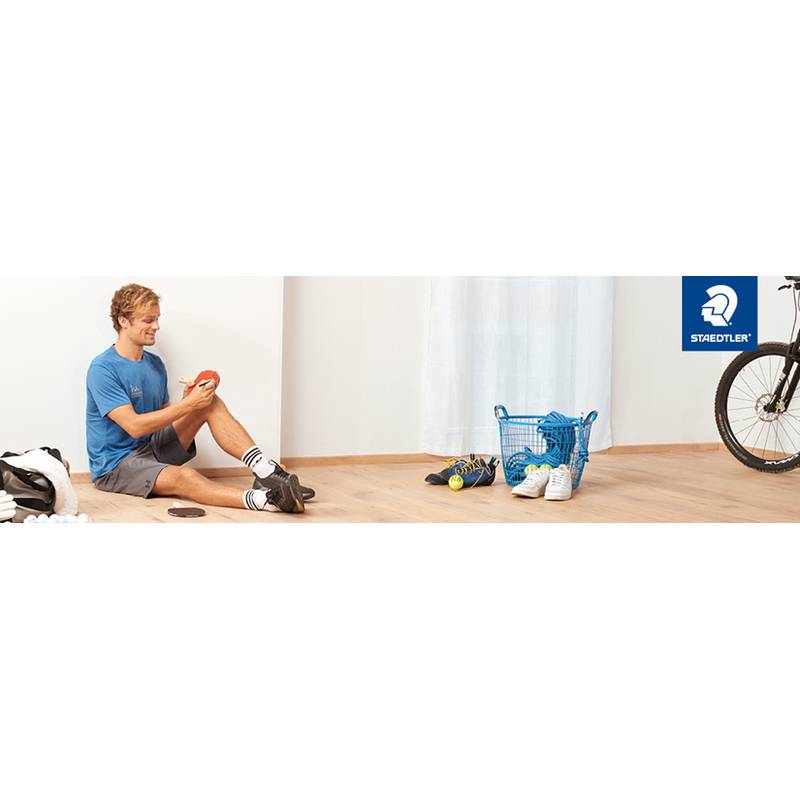 Eine Person in Sportkleidung sitzt auf einem Holzboden in der Nähe von Sportausrüstung und lächelt. Ein Fahrradreifen ist teilweise rechts sichtbar.