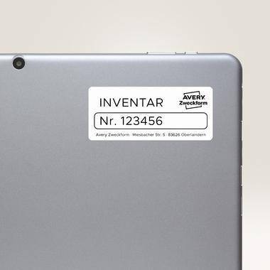 Rückseite eines silbernen Tablets mit einem weißen Avery Zweckform-Inventaretikett mit der Aufschrift 