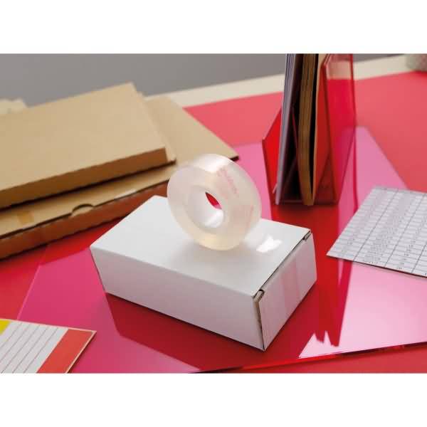 Weißer Karton mit durchsichtiger Packband-Rolle auf einer glänzenden roten Arbeitsfläche, mit flachen Karton- und Papiermustern in der Nähe.