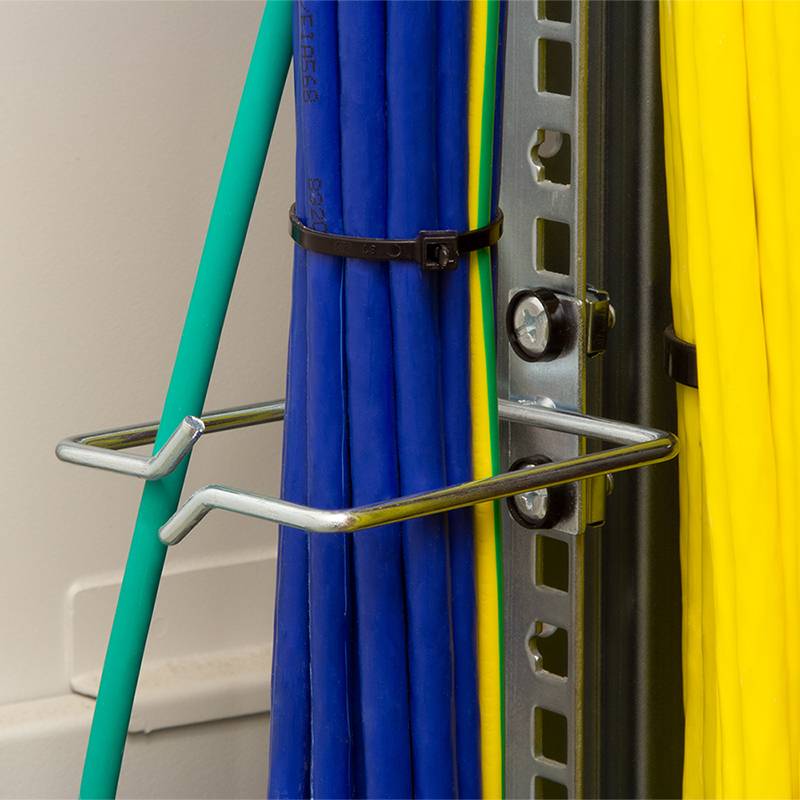 Verschiedenfarbige Kabel, einschließlich blauer und gelber, die durch Metallhalterungen an einer Wandhalterung organisiert und befestigt sind, für eine strukturierte Kabelverwaltung.