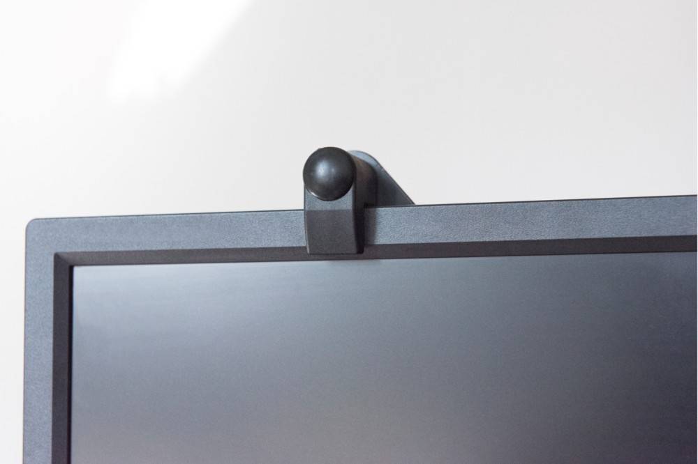 Eine Nahaufnahme eines schwarzen Computermonitors mit einem Sichtschutz über der Webcam, was den Fokus auf Sicherheit und Privatsphäre deutlich macht.