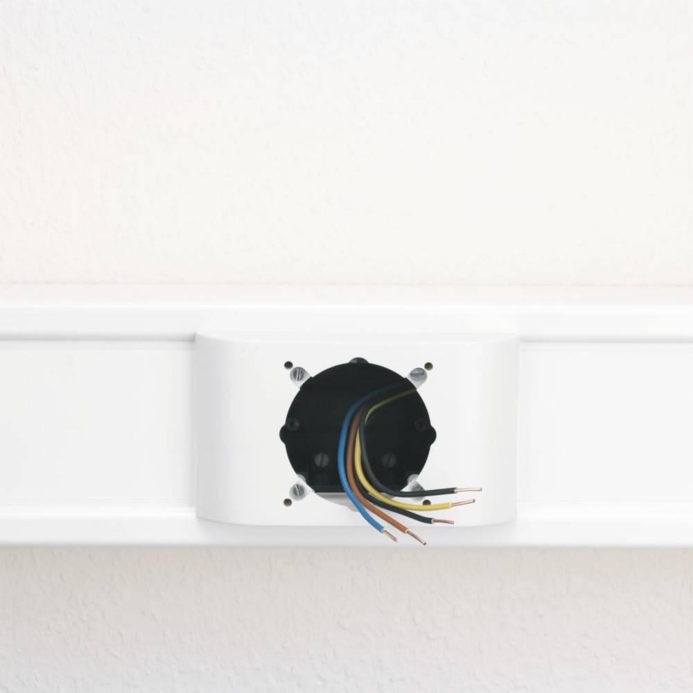 Eine elektrische Steckdose ohne Abdeckung, bei der farbige Kabel aus der Wand herausragen und laufende Elektroarbeiten andeuten.