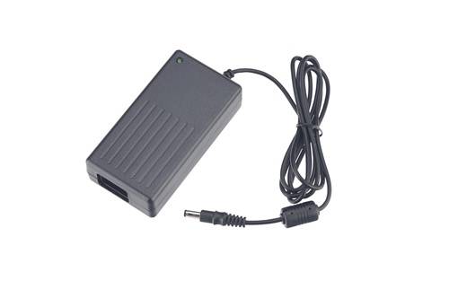 Schwarzer AC-Stromadapter mit angebrachtem Kabel und Barrel-Stecker auf weißem Hintergrund.