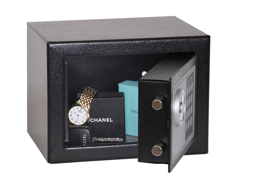 Ein offener schwarzer Tresor offenbart eine Uhr, eine Chanel-Schachtel und Papiere darin.