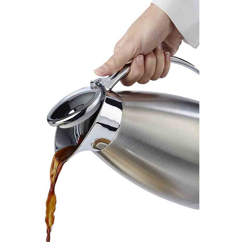 Eine Hand gießt Kaffee aus einer Edelstahlkanne in eine Tasse, wobei Flüssigkeit aus dem Ausgießer strömt.