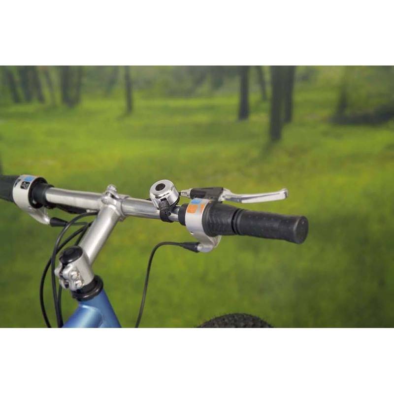 Ein Fahrradlenker mit einer Klingel und Bremshebeln, vor einem verschwommenen grünen Waldhintergrund.