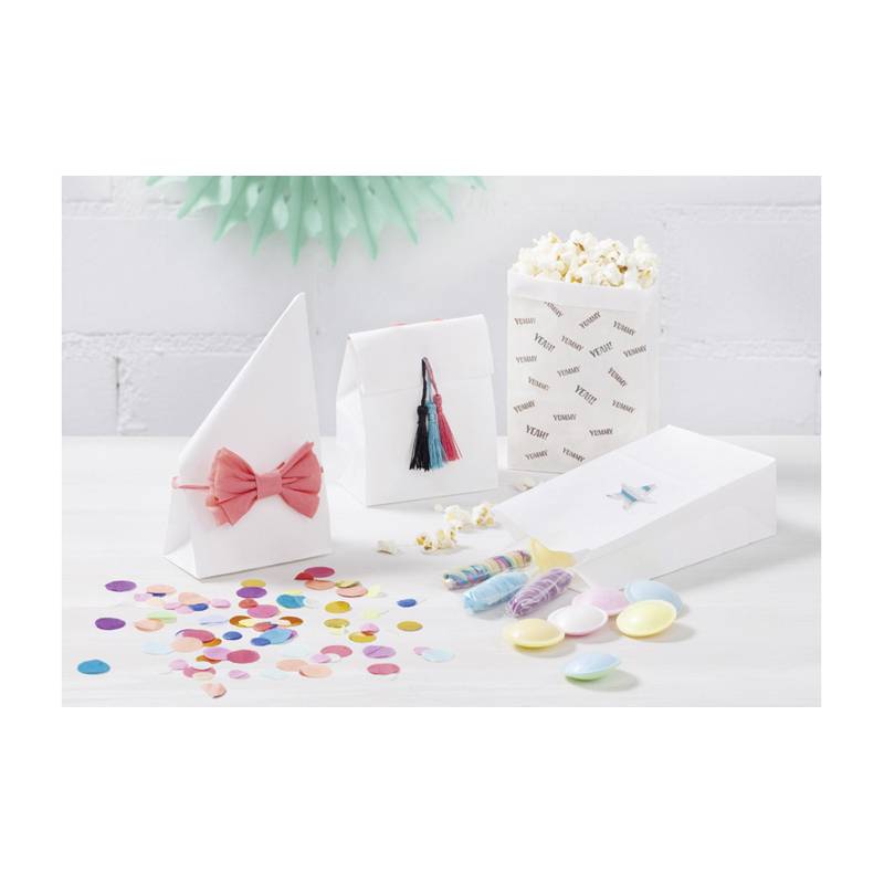 Eine Vielzahl von weißen Papiertüten, geschmückt mit Schleifen, Quasten und Konfetti, liegt auf einem Tisch, daneben eine Popcorn-Box mit der Aufschrift „YUMMM