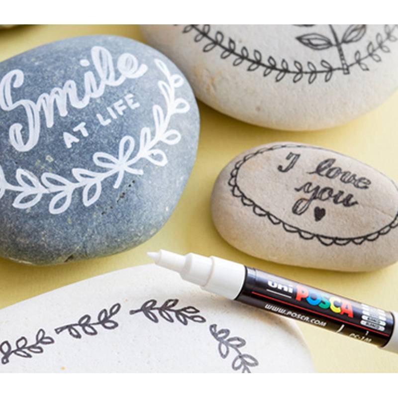 Bemalte Steine mit Botschaften; einer trägt die Aufschrift „Lächle zum Leben