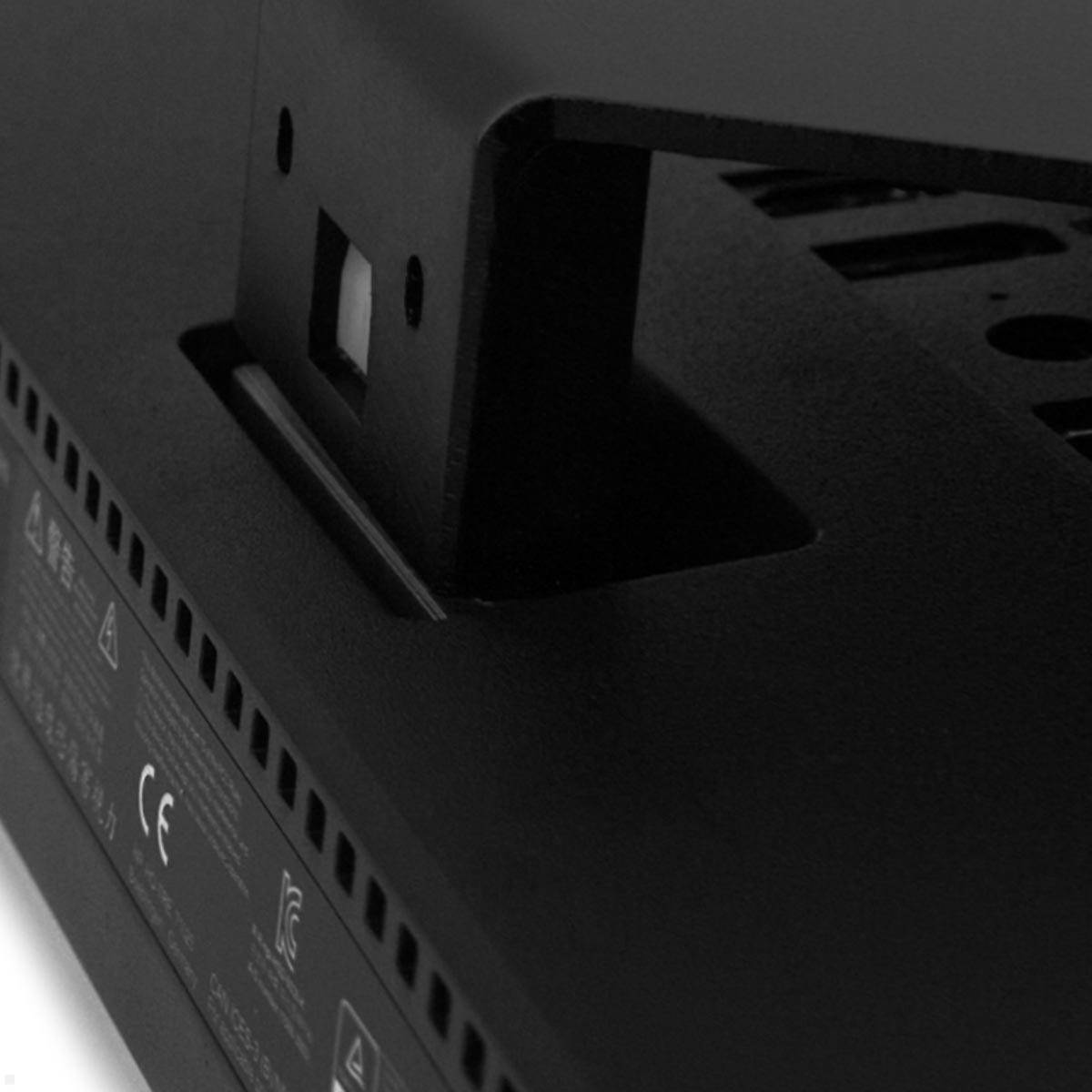 Das Bild zeigt die Rückseite eines elektronischen Geräts mit Lüftungsöffnungen und einer rechteckigen Standhalterung, die Halt und Stabilität bietet.