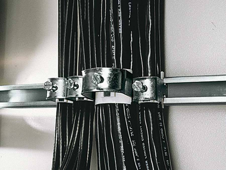 Mehrere schwarze Kabel, die mit Metallhalterungen an einer Wand befestigt sind und ein ordentliches Kabelmanagementsystem demonstrieren.