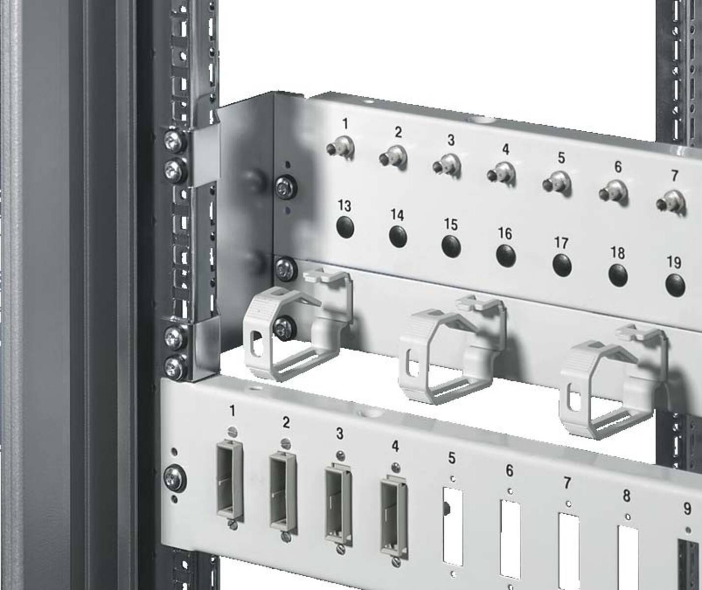 Eine Nahaufnahme eines metallenen elektronischen Rack-Panels mit nummerierten Schlitzen und Kabelverwaltungshaken, die zur Organisierung von Verkabelungen in technischen Einrichtungen verwendet werden.