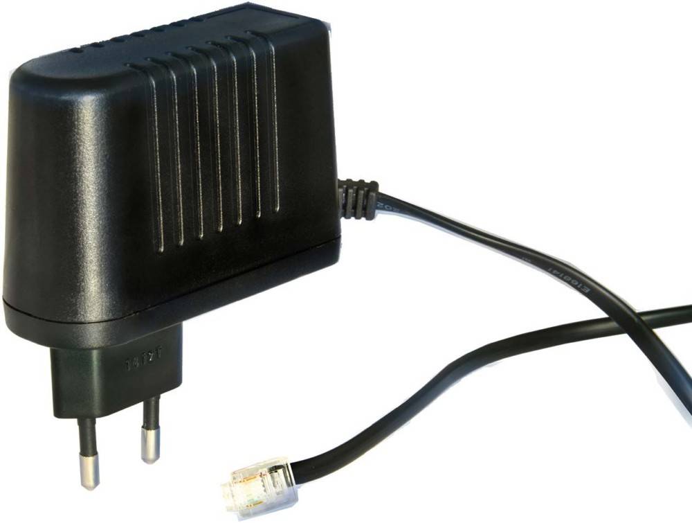 Schwarzer Stromadapter mit zweipoliger Steckdose und angeschlossenem Kabel, das in einen kleinen modularen Steckverbinder endet, vor weißem Hintergrund dargestellt.