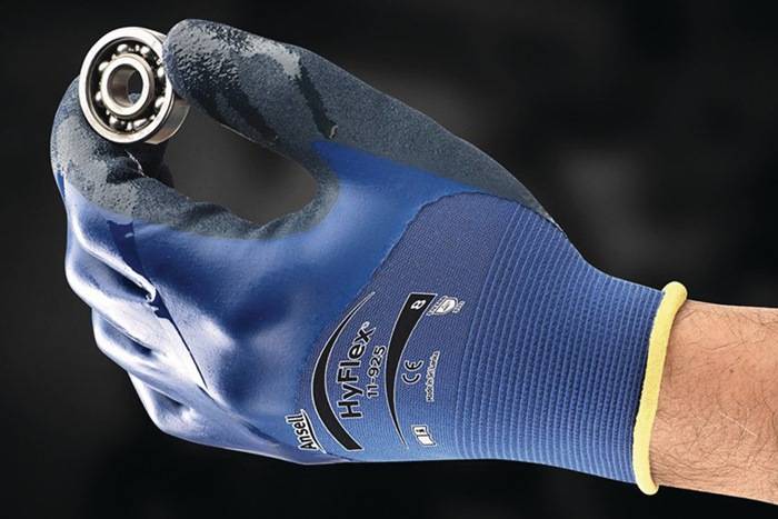 Eine behandschuhte Hand, die eine Kugellager hält. Der Handschuh ist blau und mit 