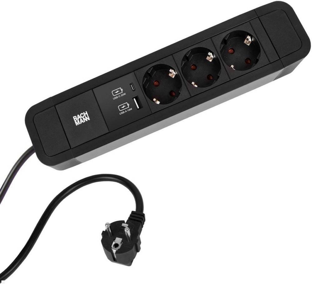 Eine schwarze Steckdosenleiste mit drei europäischen Steckdosen, zwei USB-Anschlüssen und einem angeschlossenen Kabel mit Stecker. Die Marke 'BACHMANN' ist sichtbar.