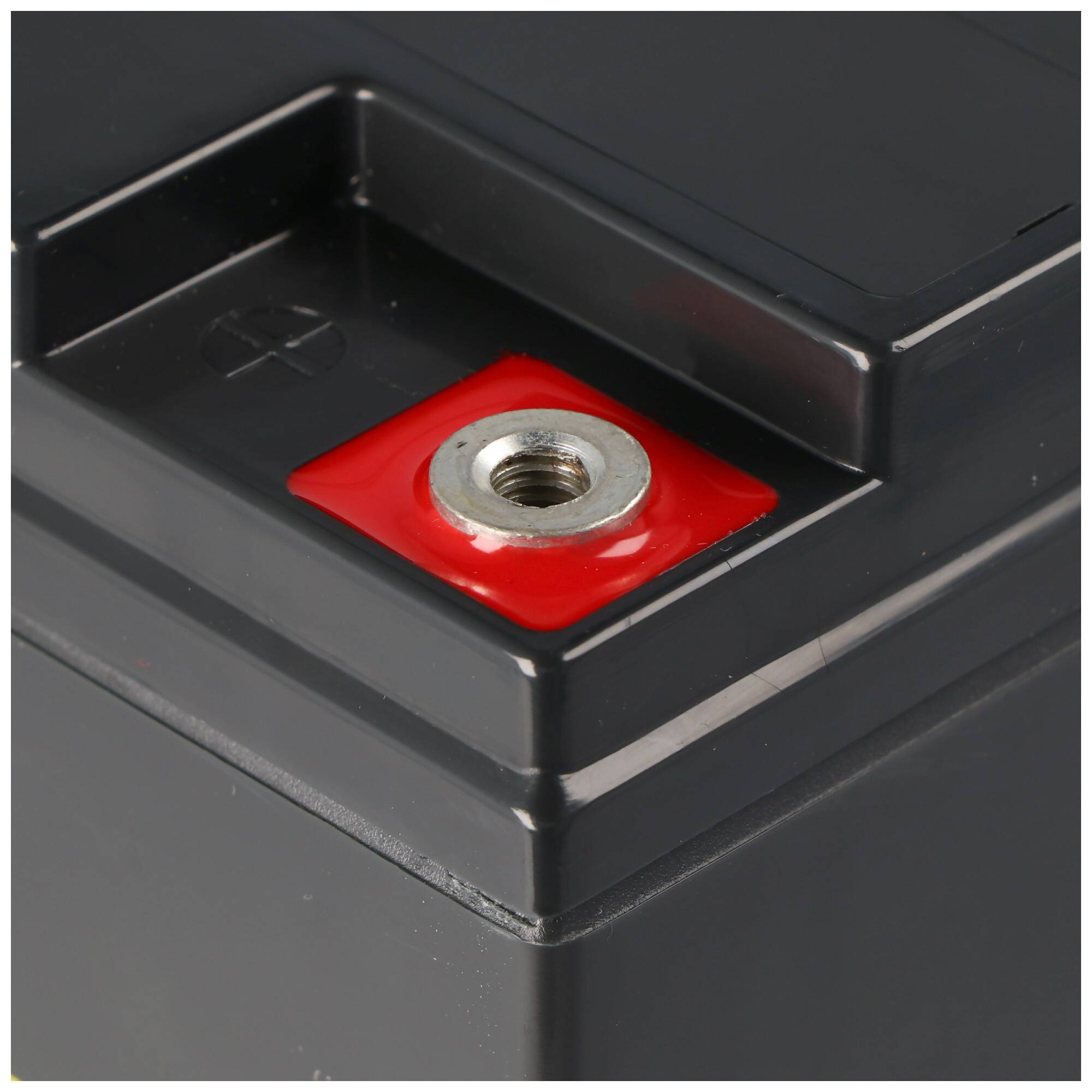 Nahaufnahme eines Batterieklemme mit rotem Pluspol-Stecker und gewindelaserte Metalleinsatz auf dunkelm Kunststoffgehäuse.