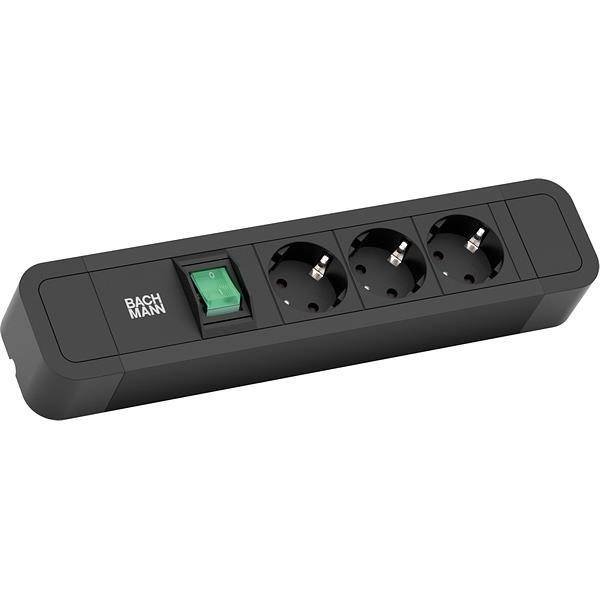 Eine schwarze Steckdosenleiste mit drei europäischen Steckdosen und einem grünen Ein-/Aus-Schalter, beschriftet mit 'BACHMANN'.