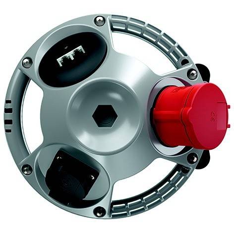 Kreisförmiges Metallgerät mit einem roten Stecker auf der rechten Seite, schwarzen Anschlüssen und einer zentralen sechskantigen Öffnung, dargestellt auf weißem Hintergrund.