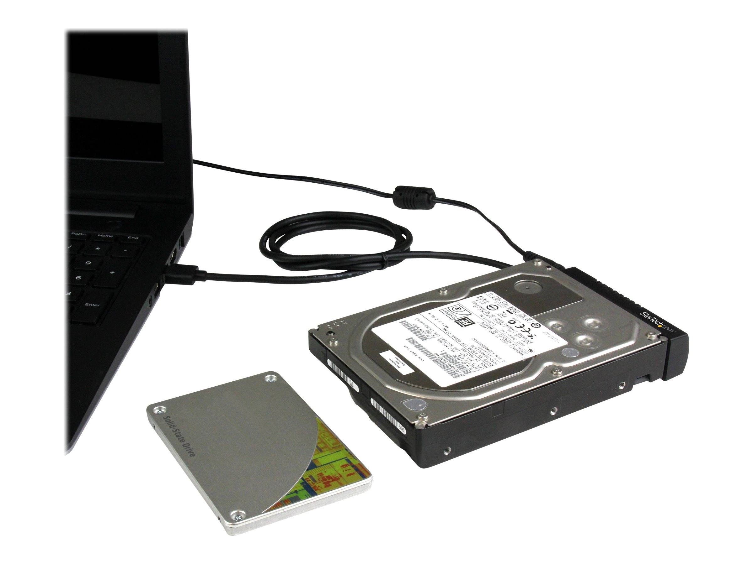 Laptop, der über ein Kabel mit einer externen Festplatte verbunden ist, mit einer separaten 2,5-Zoll-Solid-State-Drive daneben auf weißem Hintergrund.