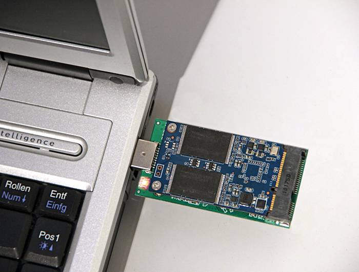 Ein USB-Anschluss eines Laptops mit einem angeschlossenen USB-Stick oder einer SSD-Speichergeräten, auf dem ein tragbares Laufwerk in Gebrauch gezeigt wird.