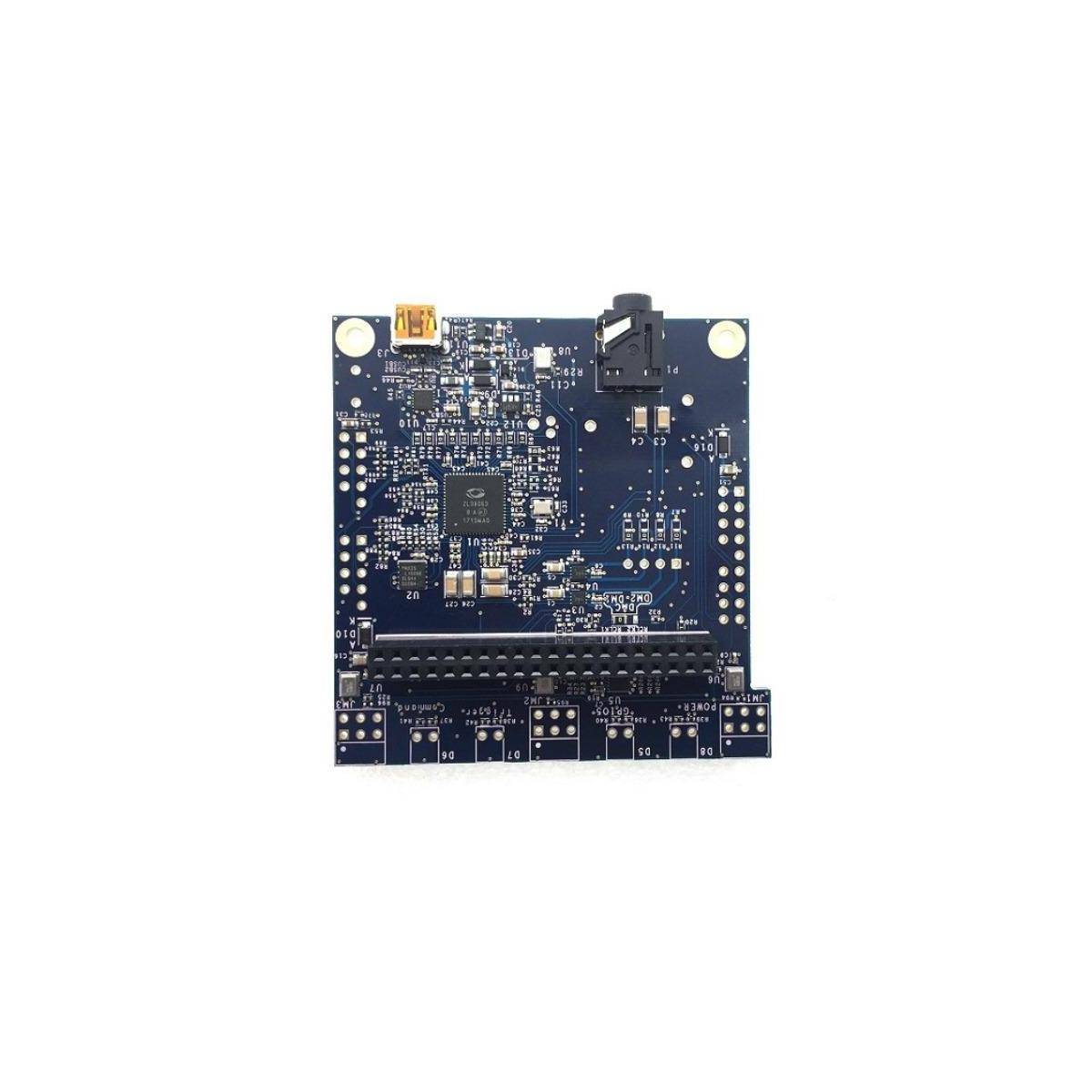 Eine kleine, blaue Leiterplatte mit verschiedenen elektronischen Komponenten, einschließlich eines zentralen Chips, Anschlüssen und Pins, auf weißem Hintergrund.