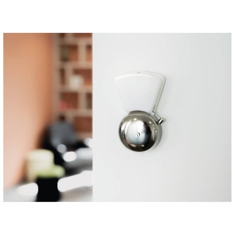 Ein modernes, wandmontiertes, kreisförmiges Thermostat an einer weißen Wand mit einem unscharfen Hintergrund, der einen Teil eines Wohnzimmers zeigt.