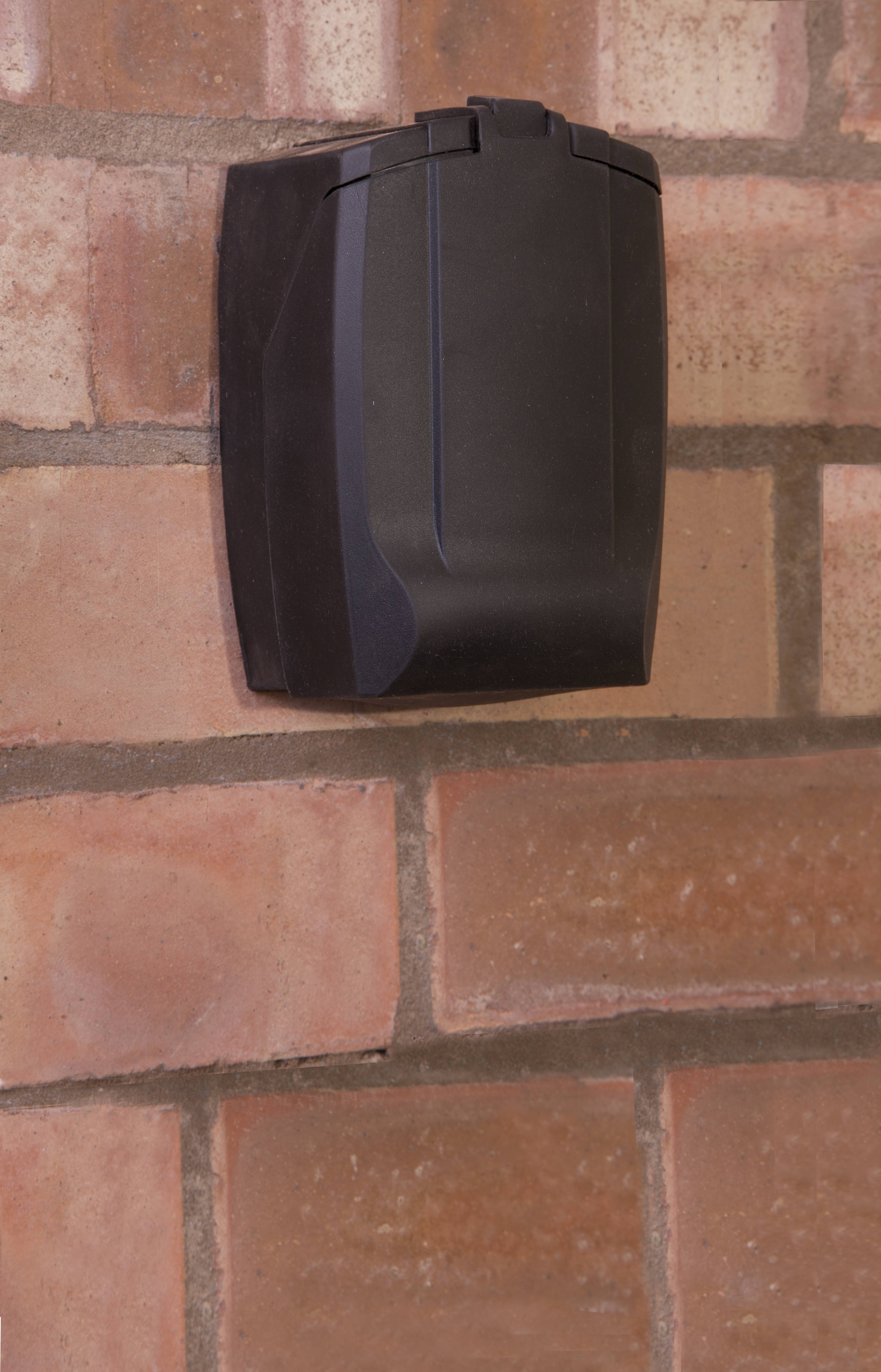Schwarzer, an einer Backsteinmauer befestigter Außengerätekastten an der Wand montiert.