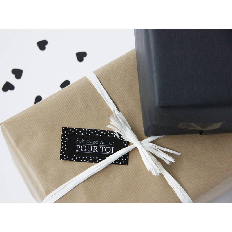 Zwei Geschenkkartons mit einfacher Verpackung; einer ist braun mit einem weißen Band und einem Anhänger, auf dem 