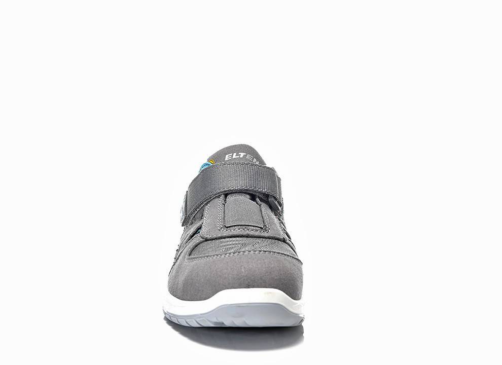Ein einzelner grauer Turnschuh mit einem Klettverschluss, weißer Sohle und Markenlogo wird vor einem weißen Hintergrund präsentiert.