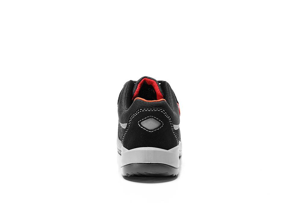 Ein schwarz-weißer Turnschuh, von hinten betrachtet, mit einer leuchtend roten Innenfütterung und einem geometrischen Design auf der Ferse.