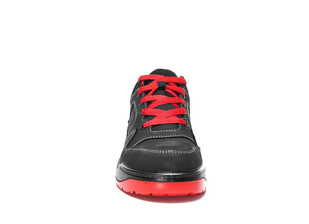 Ein schwarzer Sneaker mit roten Schnürsenkeln und roter Sohle, von vorne betrachtet, auf weißem Hintergrund isoliert.