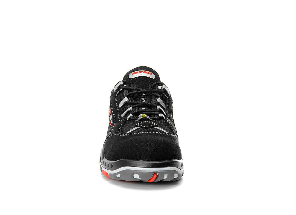 Ein schwarzer Sportschuh mit roten und grauen Akzenten, versehen mit einem auffälligen Markenlogo auf der Zunge und einer strukturierten Sohle für Griffigkeit.