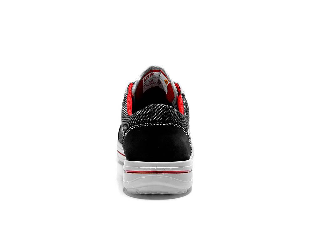 Eine schwarze und weiße Freizeitschuhe mit roter Fütterung, von hinten betrachtet, mit Profilsohle und Fersendetails.