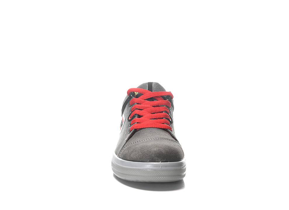 Eine Frontansicht eines grauen Sneakers mit leuchtend roten Schnürsenkeln, weißer Gummisohle und Stickereielementen, isoliert auf weißem Hintergrund.