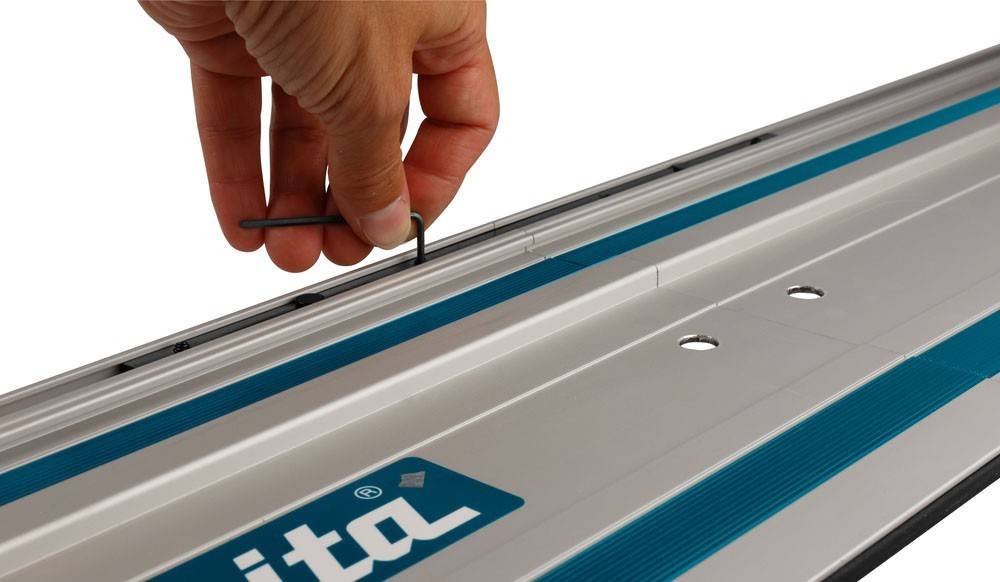 Eine Hand verwendet einen L-förmigen Sechskantschlüssel, um Schrauben an einer blau-silbernen Maschine einzustellen, mit einem Logo in der linken unteren Ecke.