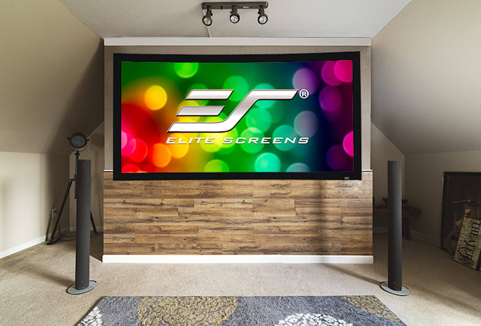 Großer Flachbildfernseher oder Projektionsleinwand in einem Heimkinobereich zeigt das Logo von "Elite Screens"" auf einem farbigen Bokeh-Hintergrund.