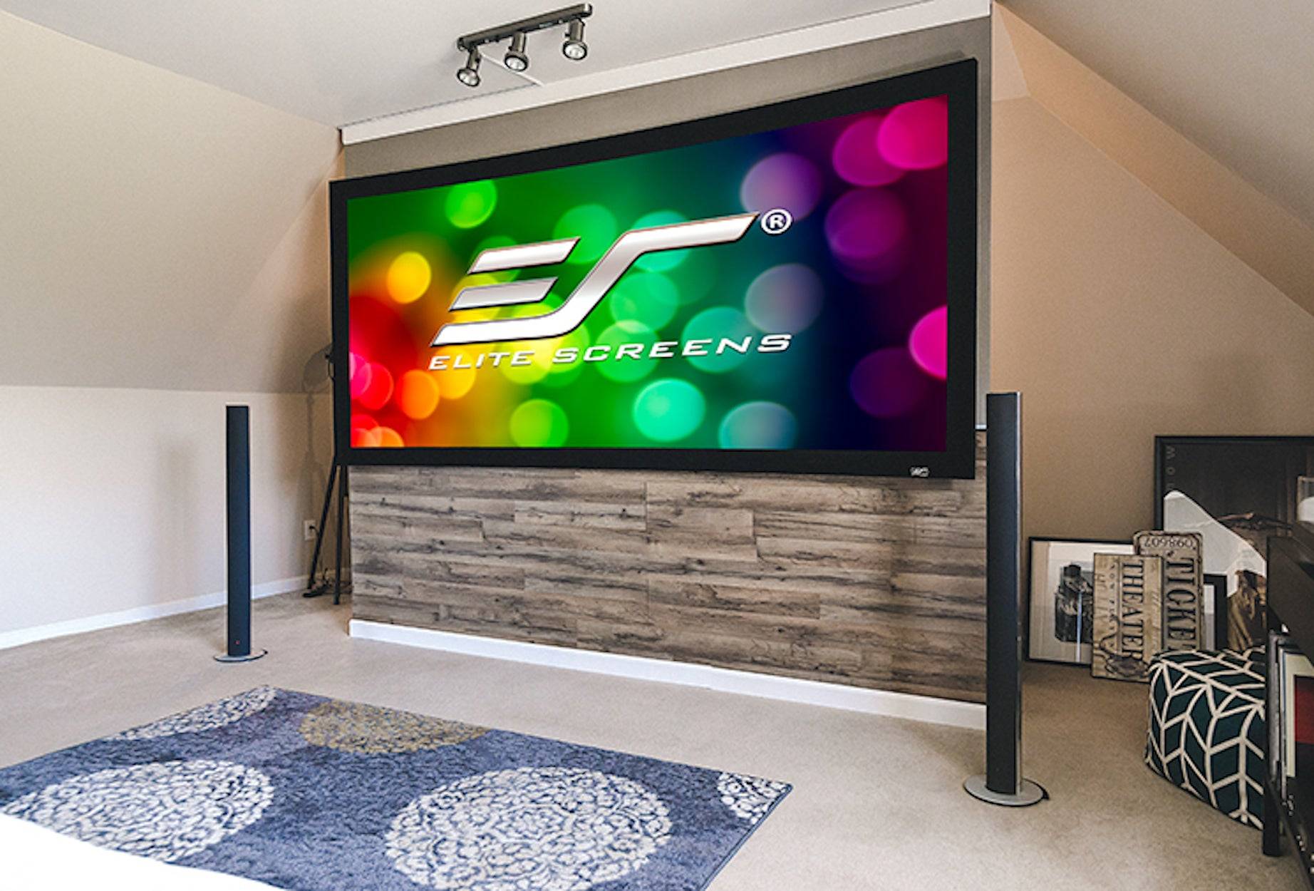 Ein großer Flachbildfernseher zeigt das farbenfrohe Logo "EP Elite Screens"" in einem Wohnzimmer oder Home-Theater-Setup, montiert über einer holzvertäfelten Konsole.