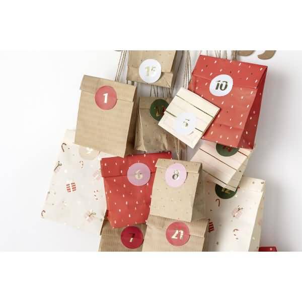 Gestapelte Papiergeschenkboxen, angeordnet wie ein Adventskalender, jede mit Nummern beschriftet, auf weißem Hintergrund.