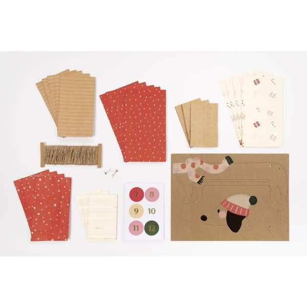 Bastelmaterialien für Papierhandwerk ausgelegt, einschließlich gemusterter Papierbogen, Schnur, Aufkleber und einer dekorierten Kartenbasis.