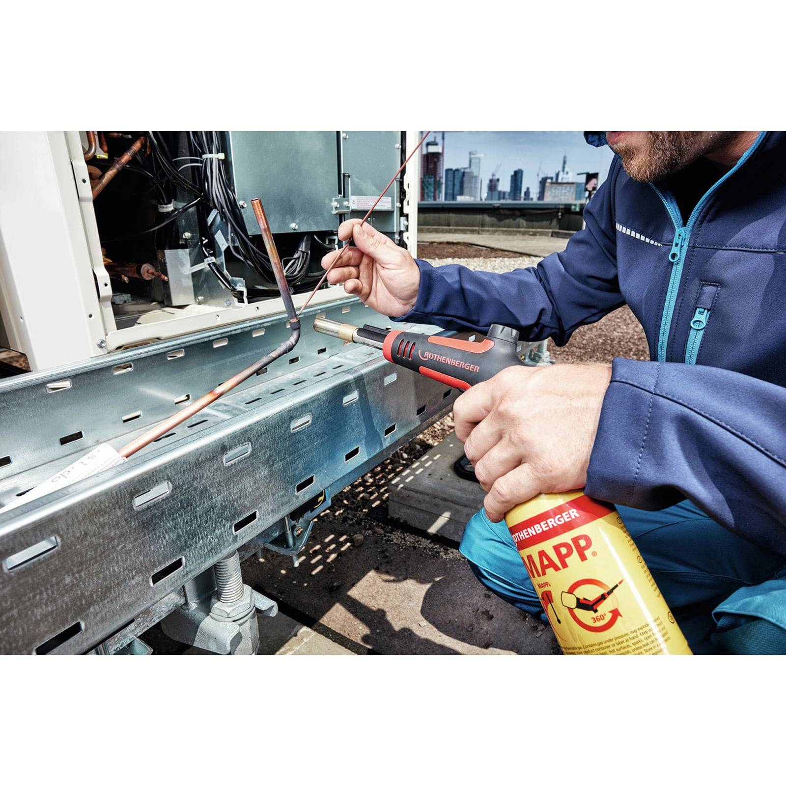 Techniker verwendet einen Propanbrenner und einen Schraubenschlüssel zum Löten oder Erhitzen von Verkabelung an HVAC-Geräten auf dem Dach.