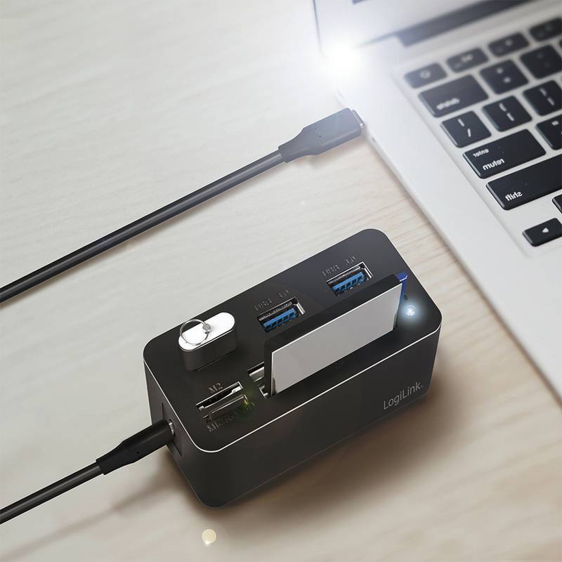 Ein USB-Hub, der mit einem Laptop verbunden ist und mehrere USB-Anschlüsse sowie Kartenslots zeigt, ermöglicht eine erweiterte Konnektivität für verschiedene Geräte.