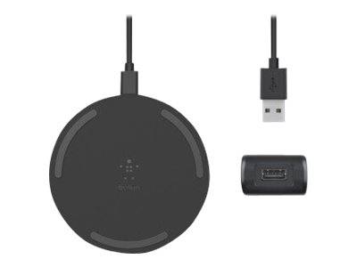 Schwarzes rundes kabelloses Ladekissen mit angeschlossenem USB-Kabel, plus ein USB-Stecker und ein kleiner Adapter daneben.