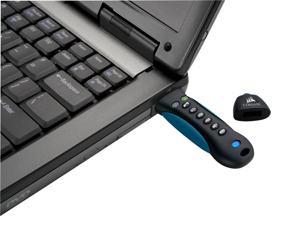 USB-Stick in die Seite eines Laptops eingesteckt, mit einer kleinen Kappe daneben auf weißem Hintergrund.