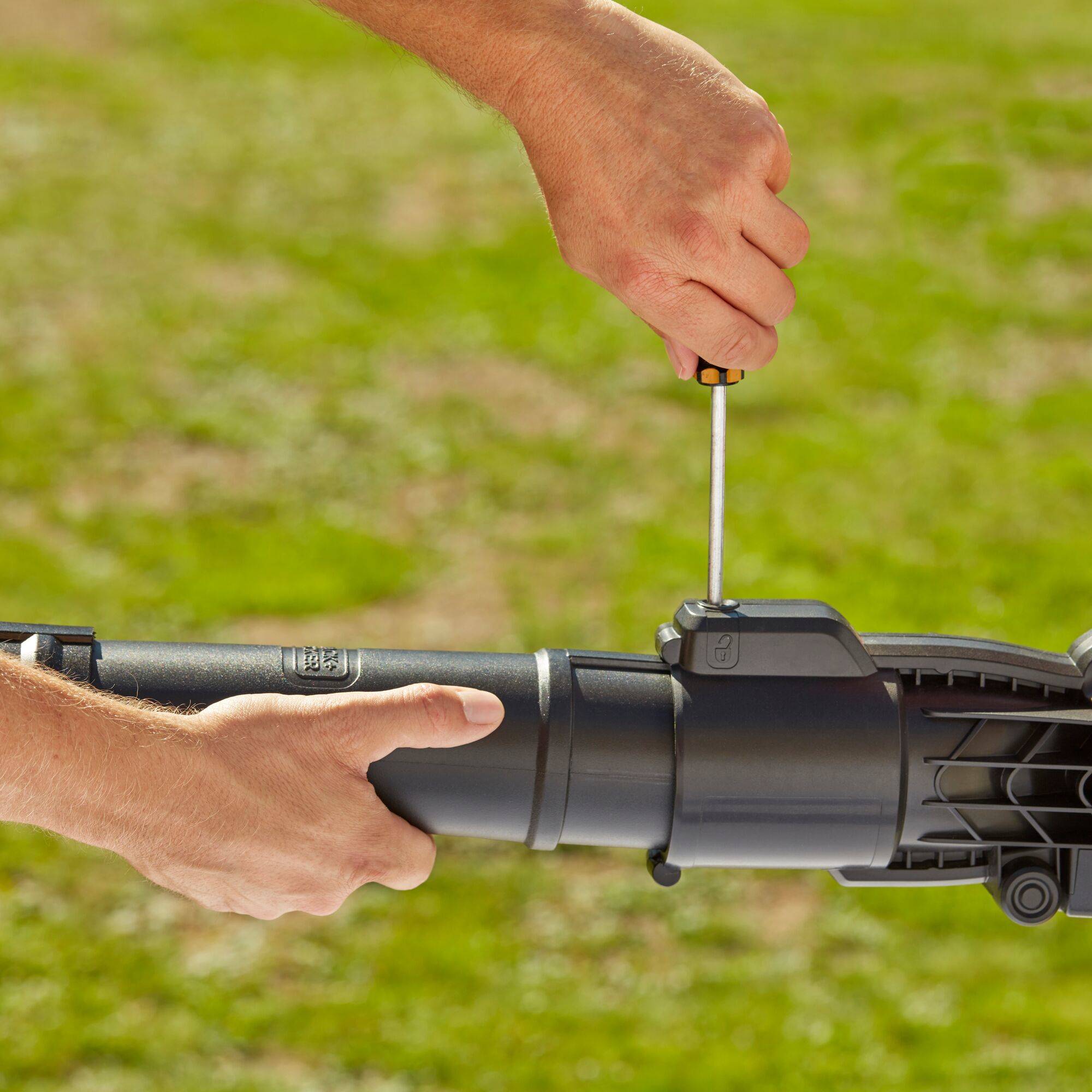 Hände, die einen Schraubendreher verwenden, um eine Schraube an einem schwarzen mechanischen Rohr oder Werkzeug im Freien festzuziehen.