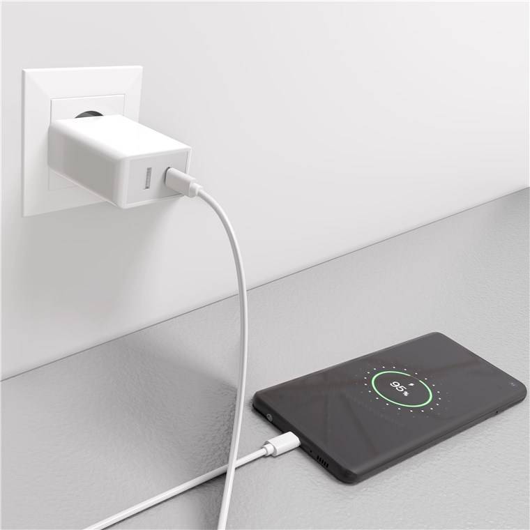 Ein Smartphone auf einem Tisch ist mit einer weißen Ladekabel an einer Wandsteckdose verbunden. Der Telefonbildschirm zeigt einen Ladestand von 90% an.