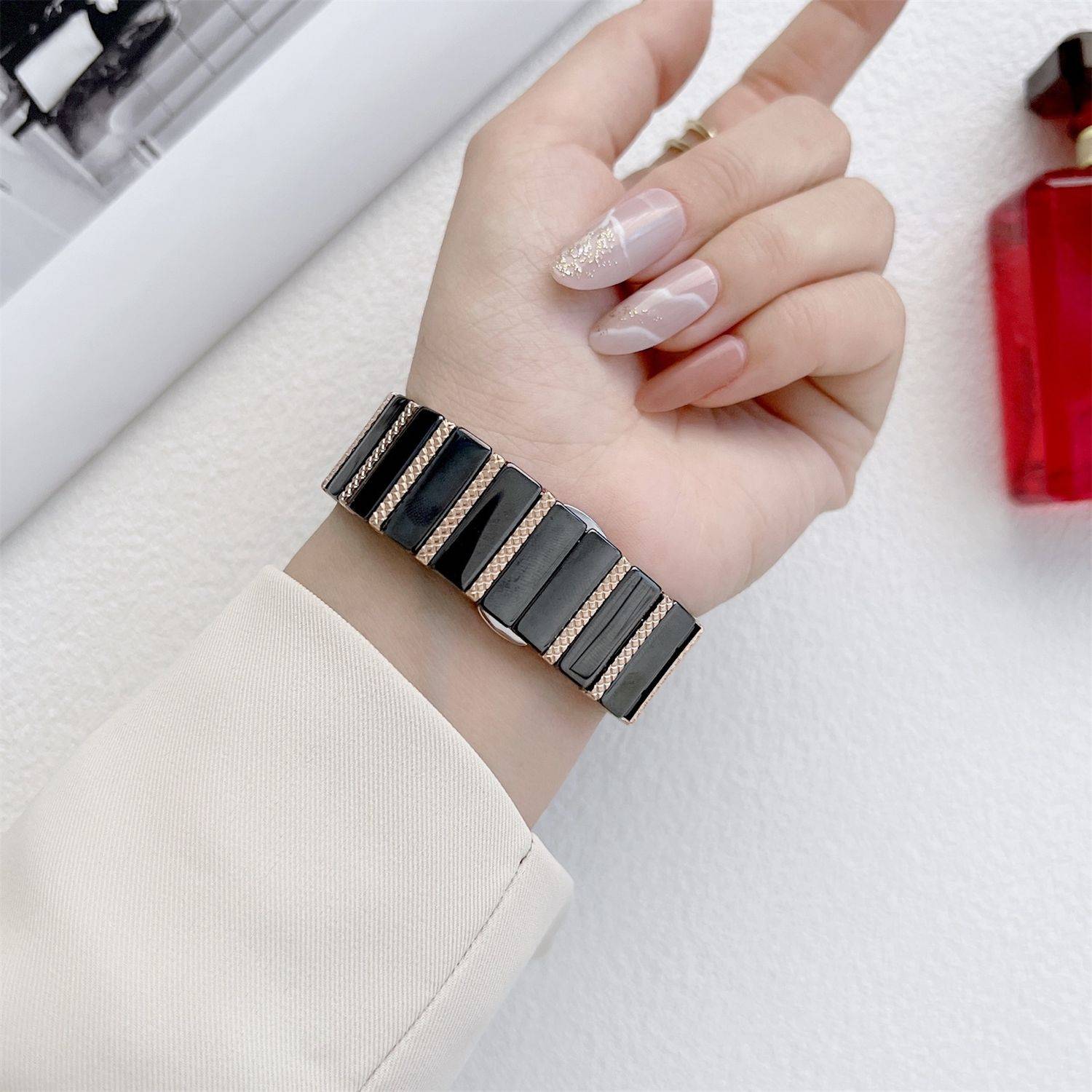 Nahaufnahme einer Hand mit einer schwarzsilbernen segmentierten Armbanduhr oder einem Armband auf einer weißen Oberfläche.